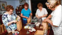  ?? FRED SQUILLANTE/COLUMBUS DISPATCH ?? Mary Ann Grove (far left), 70, a retired substitute teacher, assembles snack packs for the homeless with Marcia Candella (from left), Jackie Gerker and Ann Short.