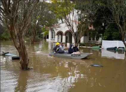  ?? Mark Baker / Associated Press ?? People paddle through a flooded street at Windsor on the outskirts of Sydney, Australia on Tuesday. Hundreds of homes have been inundated in and around Australia’s largest city in a flood emergency that was impacting 50,000 people, officials said.