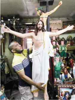  ?? (Jansen Romero) ?? RELIGIOUS BUSINESS – Store owner Noel Salino prepares an image of the Risen Christ, which is among the religious images being sold on Tayuman Street in Sta. Cruz, Manila.