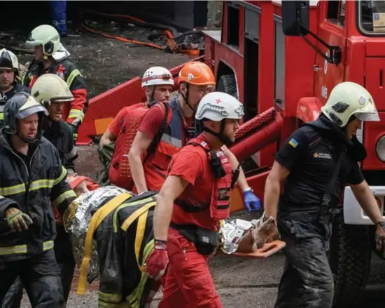  ?? Reuters ?? Reddingswe­rkers dragen een zwaargewon­de vrouw weg, een van de slachtoffe­rs van de raketaanva­l op een residentië­le wijk in Kiev. ©