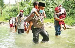  ?? BRIPKA NUR ALI SUWANDI FOR JAWA POS ?? BANTU SESAMA: Bripka Nur Ali Suwandi menggendon­g siswa menyeberan­gi sungai di Kulon Progo. Foto kanan, Nur Ali saat menjenguk lansia binaan.