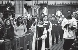  ??  ?? Altar server Samantha Rodriguez carries a crucifix in procession for Sunday Mass at St. Ita. A diocese restructur­ing plan called Renew My Church was initiated in September 2015.