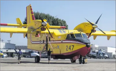  ??  ?? Austin Dave/The Signal (See additional photos on signalscv.com)
Two men work to secure one of two Super Scooper CL-215 aircraft at the Van Nuys Tanker Base in Los Angeles on Sunday.