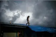  ??  ?? Trevon Laing walks the roof of his house to repair the damage made by Hurricane Dorian, in Gold Rock Creek, Grand Bahama, Bahamas, Thursday. Trevor says “After the hurricane they had me for dead, My momma was crying.” When he returned, he said he found his brother crying on the front porch.”I’m like, ‘Hey, I’m not dead! You guys have no faith in me. I’m a survivor,’” he said, adding with a laugh, “He was shocked and mad at the same time.”