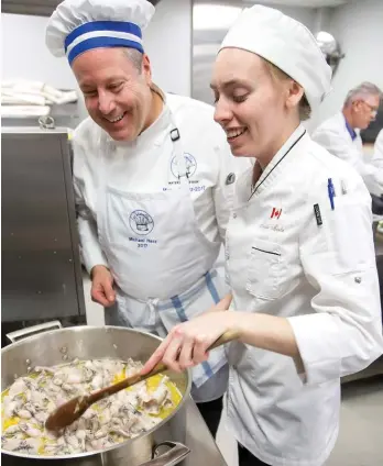  ??  ?? Chef Taylor Martin demonstrat­es her technique cooking frog legs to Michael Herz during Martin’s evening as guest chef with Les Marmitons – Waterloo Region.