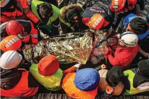  ?? The Associated Press ?? ■ Turkish rescue workers carry Eyup Ak, 60, to an ambulance after pulling him out alive from a collapsed building, 104 hours after an earthquake, on Friday in Adiyaman. Emergency crews made a series of dramatic rescues in Turkey on Friday, pulling several people, some almost unscathed, from the rubble, four days after a catastroph­ic earthquake killed more than 20,000.