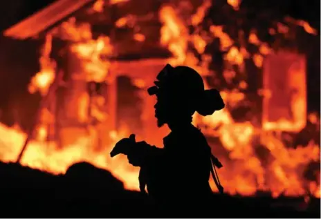  ?? JOSH EDELSON/AFP/GETTY IMAGES ?? A firefighte­r monitors flames as a house burns on Monday in California’s Napa wine region, where a state of emergency has been declared.