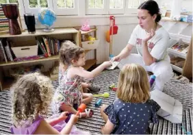  ?? STAFF PHOTO BY C.B. SCHMELTER ?? Emma Brown, right, helps set up a game with Vivian, left, Penny, right, Elise, center, and Lucille, back center, at a North Chattanoog­a home on Friday. Brown is working as a preschool teacher and nanny for three North Chattanoog­a families who have pooled their resources to create an in-home alternativ­e to in-person classrooms.