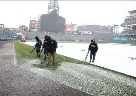  ?? THE ASSOCIATED PRESS DAVID ZALUBOWSKI/ ?? Staffers clear light snow froms Coors Field before the Colorado Rockies’ home opener against the Atlanta Braves Friday in Denver.