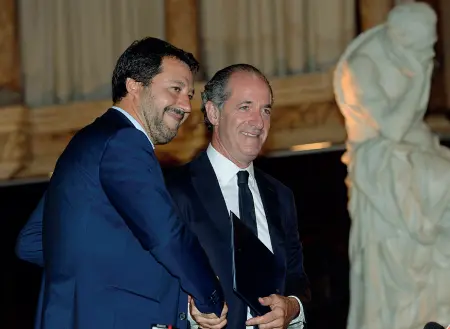  ??  ?? Divisivo A sinistra Matteo Salvini stringe la mano a Luca Zaia e viene applaudito, a destra uno striscione di protesta dei no global a Rialto (Foto Vision)