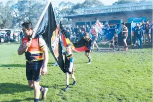  ??  ?? Left: Longwarry senior footballer Paul Williams leads out the flag bearers for the welcome to country and smoking ceremony at Longwarry Recreation Reserve on Saturday; Photograph­s: Tom Elton