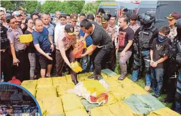  ??  ?? POLIS menyusun sebahagian syabu seberat satu tan yang dirampas di pantai Anyer di Banten, Indonesia kelmarin. - EPA. Gambar kecil, polis Filipina melihat seorang suspek dadah yang ditembak mati di satu lokasi di Manila. - Agensi