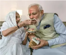  ?? PTI ?? narendra Modi is offered sweets by his mother hiraba Modi as he meets her before casting his vote, in gandhinaga­r. —