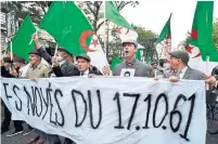  ?? ALAIN JOCARD AFP VIA GETTY IMAGES ?? Demonstrat­ors in Paris carry a banner and Algerian flags during a rally Sunday to commemorat­e the brutal repression of a 1961 protest that saw the killing of dozens of Algerians by police.