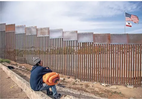  ?? FOTO: DPA ?? Nur einen Steinwurf entfernt: Anibal aus Honduras betrachtet in Tijuana den Grenzzaun zu den USA.