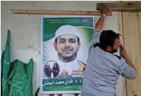  ?? - Reuters ?? ASSASSINAT­ED : A man hangs a poster depicting Palestinia­n electrical engineer Fadi Al Batash, who was shot to death in Malaysia, on his family house in the northern Gaza Strip April 21, 2018.