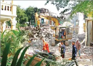  ?? HENG CHIVOAN ?? A monk looks on as an excavator demolishes one of three monastery buildings at Wat Ounalom in the capital’s Daun Penh district on December 12.