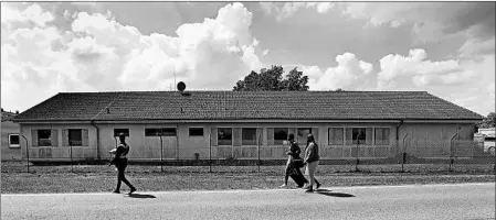  ?? ALEXANDRA BEIER/GETTY ?? Residents pass by the Bavarian Transit Center last week in Ingolstadt, Germany. The transit center houses asylum seekers who will likely be deported.