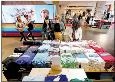  ?? AP ?? Shoppers look over a T-shirt display in the Levi’s store in New York’s Times Square in June. Clothing prices increased 0.4% last month, the Labor Department said Tuesday.