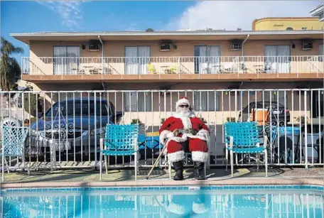  ?? Photograph­s by Jay L. Clendenin Los Angeles Times ?? AN EXTRA in a Santa costume gets into “background” position at a Hollywood Boulevard motel during Season 3 shooting for “Fargo.”