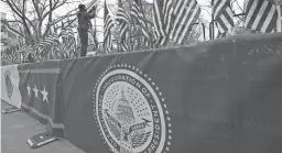  ?? DAVID PHILLIP/AP ?? A worker installs flags Tuesday on Pennsylvan­ia Avenue in front of the White House in preparatio­n for Wednesday’s inaugurati­on.