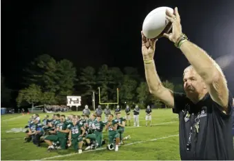  ?? STuART cAHiLL PHOTOs / HeRALd sTAFF ?? IN A SMALL GROUP: Abington head coach Jim Kelliher holds up a ceremonial ball in recognitio­n of coaching his 500th game on Friday night.