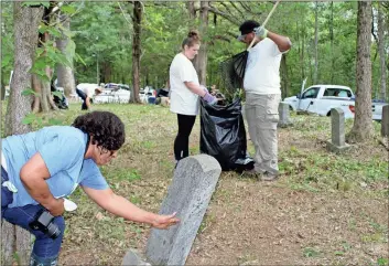  ?? / Doug Walker ?? Janis Boone (from left) tries to feel informatio­n on a headstone at the historic Zuber Cemetery while Berry students Katie Henrich and Ross Bryant help with the cleanup at the cemetery Saturday.