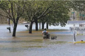 ?? Carlos Osorio / Associated Press ?? Waters overflow the Tittabawas­see River, in Midland, Mich., a city of 42,000 people. Some 10,000 residents from have been forced to evacuate.