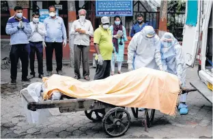  ?? ADNAN ABIDI/FILE • REUTERS ?? Health workers cover the body of a man who died due to the coronaviru­s, as relatives pay their respects, at a crematoriu­m in New Delhi, India, Thursday.