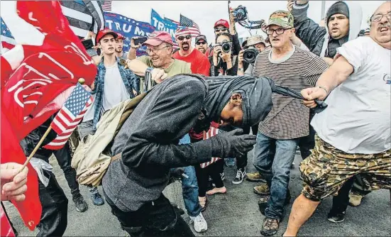  ?? IRFAN KHAN / AP ?? Tensión en la calle. Un activista anti-Trump es zarandeado por manifestan­tes pro-Trump que marchaban en Huntington Beach (California), al sur de Los Ángeles