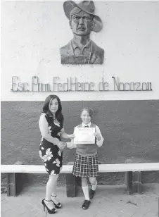  ??  ?? La pequeña Hanna Camila recibe diploma de reconocimi­ento de la directora del plantel, Juana María García.