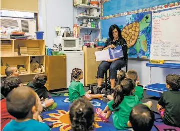  ?? CHRISTOPHE­R GREGORY/THE NEW YORK TIMES ?? Lisa Martino, who is enrolled in a city-funded master’s degree program in early childhood education, reads to students in 2014 in preparatio­n for a job as a pre-K teacher, at St. Pancras School in New York. While data shows that teachers’ level of...