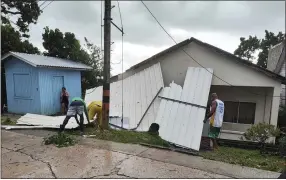  ?? DANIEL PARRA — THE ASSOCIATED PRESS ?? Men pick up a damaged roof in the aftermath of Hurricane Julia in San Andres island, Colombia, Sunday, Oct.9, 2022. Hurricane Julia hit Nicaragua’s central Caribbean coast on Sunday after lashing Colombia’s San Andres island, and a weakened storm was expected to emerge over the Pacific.