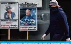  ??  ?? VIRGINIA: A man wearing a face mask walks past signs for Joe Biden’s 2020 presidenti­al campaign amid the coronaviru­s outbreak in Alexandria, Virginia. — AFP