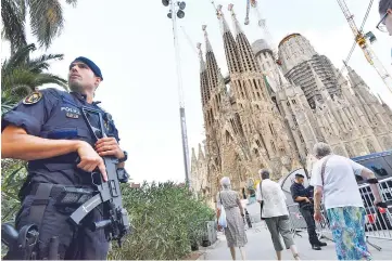  ??  ?? A police officer stands by the Sagrada Familia basilica in Barcelona, before a mass to commemorat­e victims of the two devastatin­g terror attacks in Barcelona and Cambrils. — AFP photo