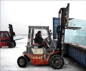  ??  ?? Forklift operators loading ice blocks from the frozen Songhua river onto waiting trucks.