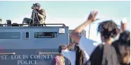  ?? JEFF ROBERSON/ASSOCIATED PRESS ?? A member of the St. Louis County Police Department points his weapon in the direction of a group of protesters in Ferguson, Mo., on Aug. 13, 2014. On Aug. 9, 2014, a white police officer fatally shot Michael Brown, an unarmed black teenager, in the St....