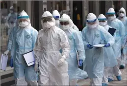  ?? VINCENT THIAN — THE ASSOCIATED PRESS ?? Medical workers in protective suits enter a building under lockdown in downtown Kuala Lumpur, Malaysia, on Tuesday.