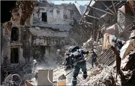  ?? ?? Shelled: Donetsk People’s Republic workers clear rubble at a Mariupol theatre