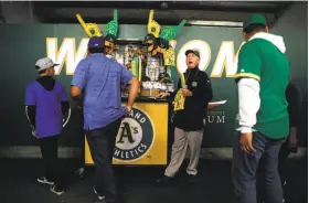  ??  ?? Vendor Tim Begley, who has worked at the Coliseum for 39 years, hawks souvenirs before the A’s-Dodgers game Wednesday, which drew 32,062 fans.