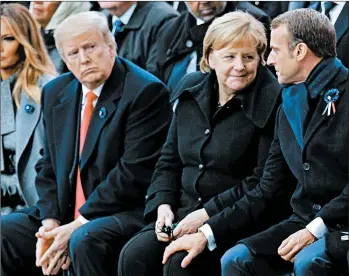  ?? FRANCOIS MORI/GETTY-AFP ?? French President Emmanuel Macron and German Chancellor Angela Merkel sit with President Donald Trump and first lady Melania Trump on Sunday at the Arc de Triomphe in Paris.