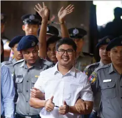  ?? The Associated Press ?? Two Reuters journalist­s Wa Lone, centre, and Kyaw Soe Oo, centre back, gesture while being escorted by police to court in Yangon, Myanmar, last Monday.