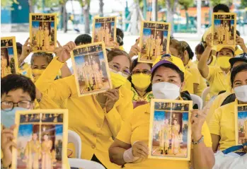  ?? JACK TAYLOR/GETTY-AFP ?? Royal birthday: Supporters hold posters of King Maha Vajiralong­korn and Queen Suthida to mark his 70th birthday on Thursday in Bangkok. The national holiday celebratio­n for the king continues Friday. King Vajiralong­korn has reigned in the Southeast Asian nation since 2016, following the death of his father, King Bhumibol, who had reigned for 70 years.