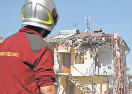  ?? ANDREAS SOLARO, AFP/ GETTY IMAGES ?? Firefighte­rs knock down rubble hanging precarious­ly from a damaged building in Amatrice on Sunday. The death toll in the town stood at 229. Shoddy constructi­on could be to blame for the collapse of some structures, said prosecutor Giuseppe Saieva, who...