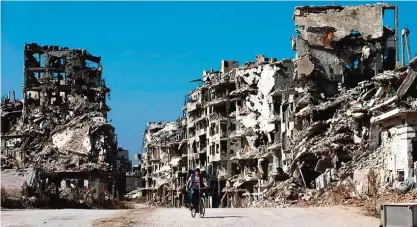  ??  ?? HOMS: A Syrian boy rides a bicycle through a devastated part of the old city.