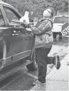  ??  ?? A worker with the Warrick County School Corp. in southern Indiana carries a tray of meals to a waiting car on May 8.