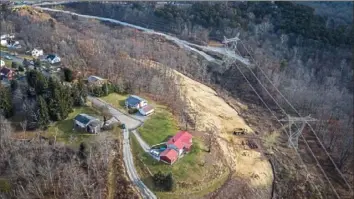  ?? Andrew Rush/Post-Gazette ?? The path of a new 12-inch natural gas pipeline being built by National Fuel crosses Energy Transfer's Revolution pipeline behind the house with the red roof. This photo, taken in December, shows the cleared right of way for both pipelines. Energy Transfer has since purchased the red-roofed home.