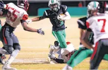  ??  ?? Bishop McGuinness’ Tyler Travis breaks a tackle during Friday’s high school football playoff game against Del City. Bishop McGuinness won, 28-21.