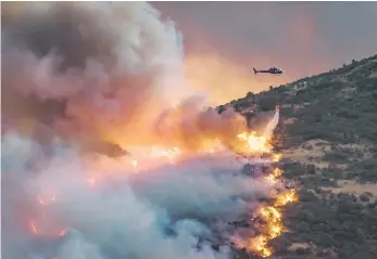  ?? — Reuters photo ?? A helicopter dumps fire retardant on wildfires near Christchur­ch on New Zealand’s South Island.