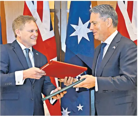  ?? ?? Grant Shapps, the British Defence Secretary, and Richard Marles, his Australian opposite number, exchange treaty documents at Parliament House in Canberra